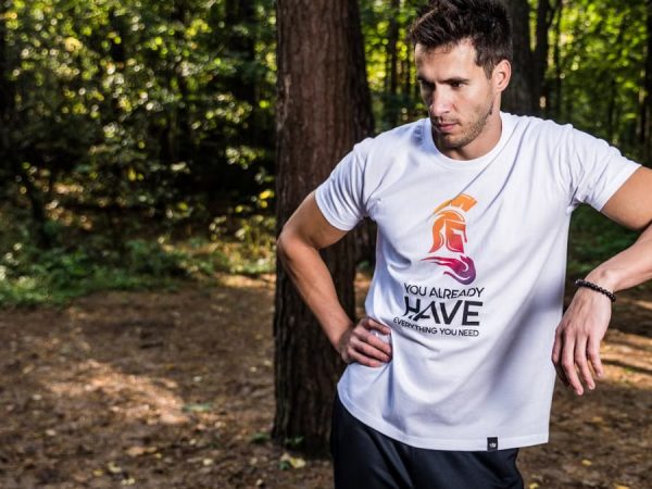 Man in forest wearing casual t-shirt, resting during outdoor workout.